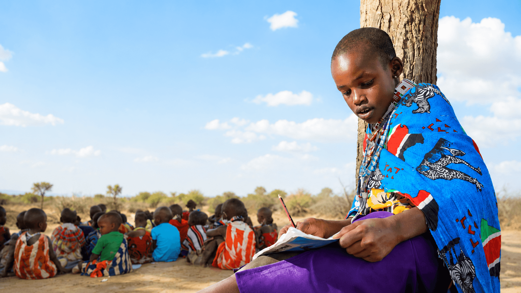 A child writing in a notebook outdoors at Moyo Academy in Kenya