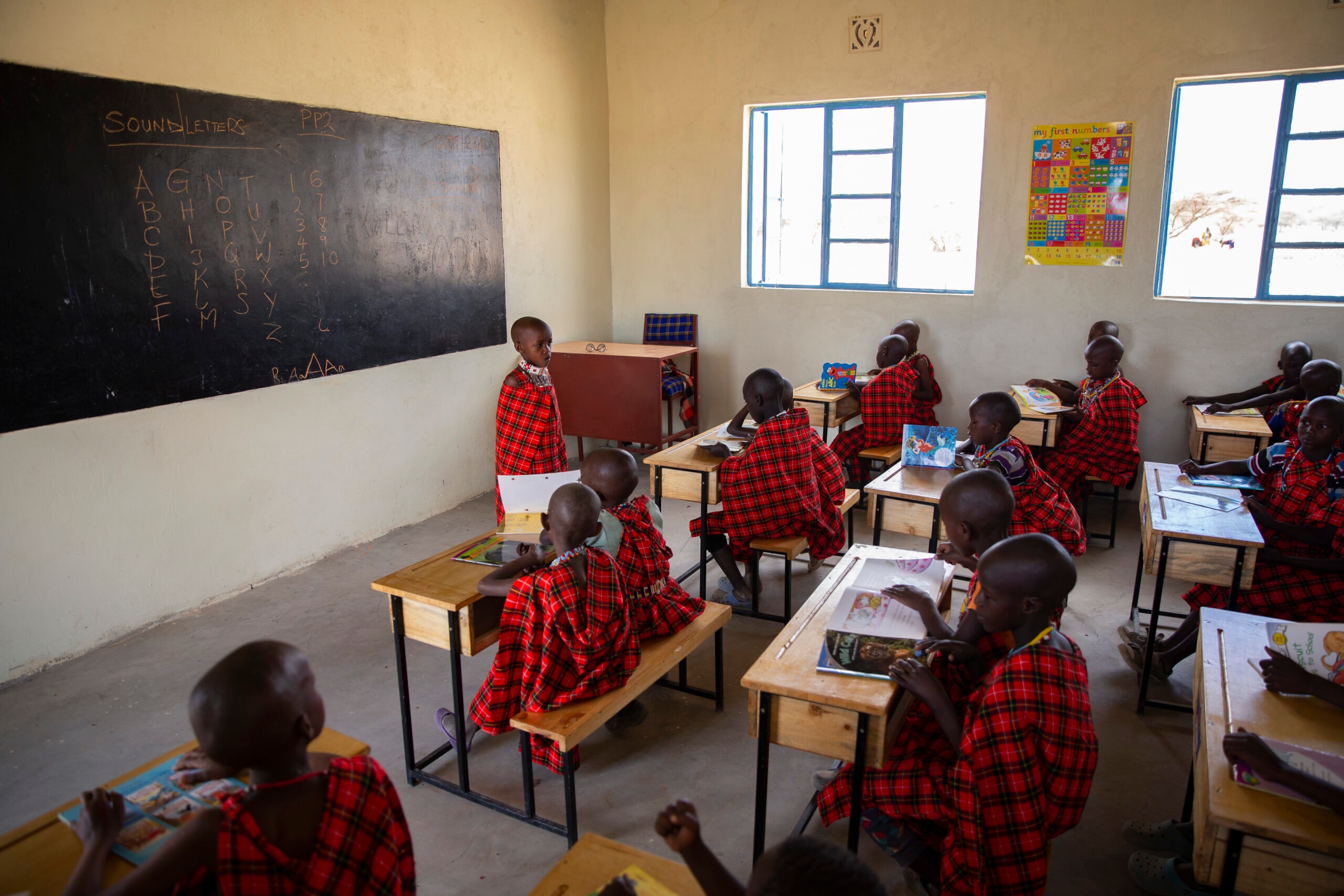 Children sitting at desks with books in a classroom