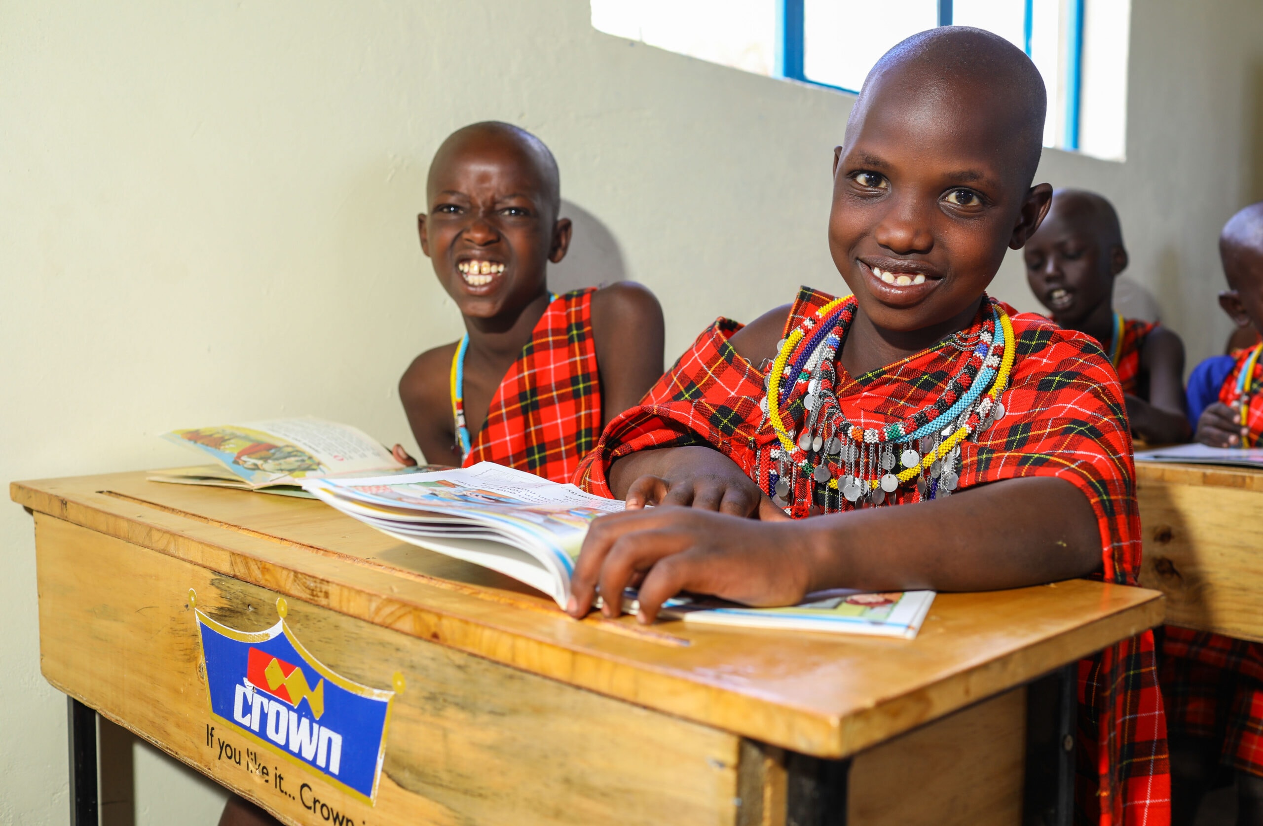A smiling child with an open book at a classroom desk